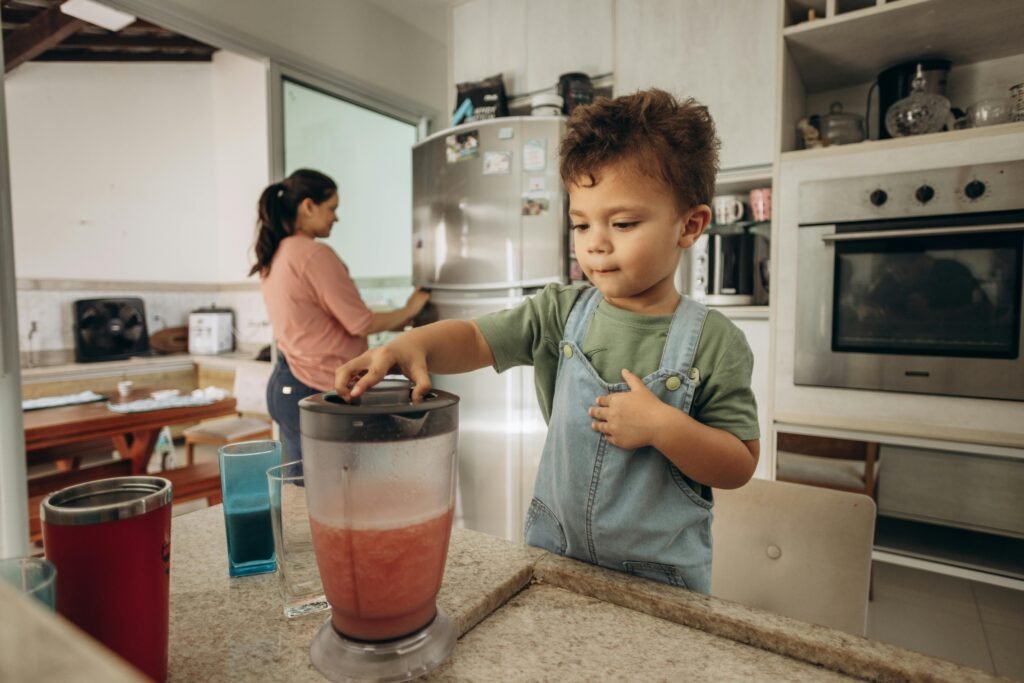 pexels-photo-19773968-19773968 A young boy helps his mother make a smoothie using a blender in a modern kitchen.