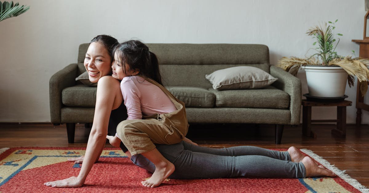 A joyful mother practicing yoga with her daughter on a colorful rug indoors.