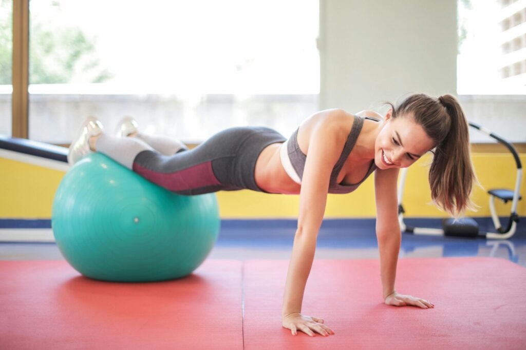 Active woman performing a workout with a stability ball indoors, showcasing fitness and strength.